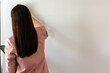 © WARAPHON - Woman in pink blazer stands before blank white wall. Long dark hair flows smoothly down her back. She appears focused, reaching upward with calm intent. Ideal for minimalist design