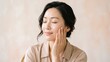 © NovaluneNL - Young Asian Woman With Radiant Glowing Skin Gently Touching Her Face in a Serene Portrait for Skincare and Natural Beauty Wellness Concept