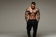 © Pete - Muscular man with full body tattoos walks forward. He has a toned physique, strong abs, and wears black sweatpants. Confident male model posing for studio photo.