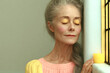 © Jounn - Serene mature woman with gray hair and closed eyes resting beside a glowing candle, conveying mindfulness, relaxation, and emotional wellness.