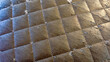 © Newleks - Worn quilted brown synthetic leather upholstery with cracked texture and peeling surface showing damage from wear, a deteriorating fabric background
