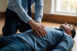 © Maryna - Business man in shirt performs chest compressions on unconscious colleague lying on office floor. Employee provides first aid help to co-worker during sudden heart attack emergency. Pro rescuer