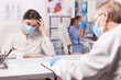 © DC Studio - Young woman wearing a protective mask cries during a hospital examination with a doctor, suggesting fear, illness concern and clinical support.