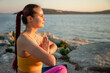 © ADDICTIVE STOCK - Woman meditating in yoga pose by the sea at sunset