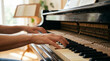 © Matos - Close up of hands playing an old upright piano with sheet music in the background