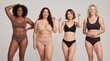 © Karan - Diverse group of happy young women in matching underwear posing together against a neutral studio background