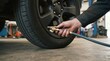 © SimpleDesignStudio - Professional mechanic inflating a car tire with compressed air in an auto repair shop
