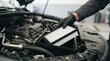 © SimpleDesignStudio - Professional mechanic changing the air filter in a car engine bay during routine maintenance