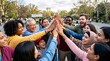 © Sudarti - Diverse group of multiracial people and family members putting their hands together in a high five outdoors in a park to celebrate unity, community, and teamwork.
