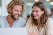 © lashkhidzetim - Two people share a joyful moment while using a laptop. They smile warmly, focused on the screen together. Their relaxed expressions convey mutual enjoyment and connection. Ideal for scenes of teamwork