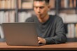 © AK ST - Young Man Working on Laptop at Desk in Modern Home Office Setting