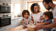 © Jumain - Parents and children baking homemade cookies together in the kitchen.