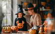 © Konstantin Yuganov - Mother and Daughter in Witch Costumes Enjoying Halloween Pumpkins