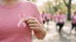 © velikiyzayats - Woman wearing pink shirt holding breast cancer awareness ribbon during charity walk event symbolizing health support and survival