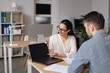 © Prostock-studio - Focused Young Hispanic Woman Talking To Male Colleague In Office While Presenting Data On Laptop Screen. Engaging Discussion Taking Place In Modern Workspace Setting. Business Concept.