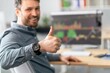 © Prostock-studio - Smiling Caucasian Man In His 30s Giving Thumbs Up While Sitting At His Desk In Office Environment, Showing Confidence And Positivity In Business Settings. Business Concept.