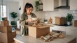 © ISVO - Woman unpacking kitchenware from a cardboard box on a kitchen countertop, surrounded by moving boxes and plants in a modern home interior