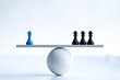 © ATIKUL ISLAM - Chess pawns on balance scale one blue pawn opposite three black pawns concept of inequality power strategy or unequal opposition