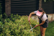 © Roman - Woman pruning bushes in a backyard garden