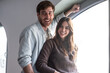 © luciano - Happy young couple smiling and laughing, enjoying life together, standing by a window with natural light, feeling joy and connection
