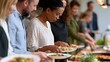 © Thares2020 - People lining up to serve themselves food at a buffet style meal event indoors with warm lighting
