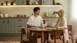 © shine.graphics - Couple holding hands across a table during a meal in a modern kitchen
