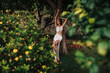 © ADDICTIVE STOCK - Young woman in white dress posing by tree in lush garden