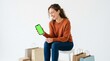 © Andressa - Woman laughing while looking at a green screen smartphone surrounded by shopping bags and boxes