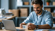 © Nataliya - Cheerful man opening a cardboard parcel near his laptop, small business packaging background, with copy space