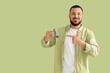 © Pixel-Shot - Young man pointing at inhaler on green background