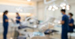 © RealTech - A blurred image depicting a dental clinic with dental professionals in blue scrubs working. The modern environment features dental equipment and bright lighting.