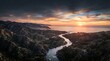© MST. REHENA BEGUM - Aerial view of a winding river flowing through a mountainous landscape towards the sea at sunset with dramatic clouds and golden light on the horizon