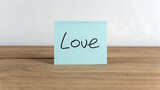 Handwritten love note on sticky paper for Valentine's Day. Romantic message card on wooden table for wedding or anniversary celebration.