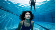 © Jamina - Woman underwater in a swimming pool looking up at a man standing above