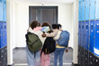 © Wavebreak Media - African American teen females walking arm-in-arm in school hall by blue lockers carrying backpacks