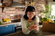 © Davor - Young woman using smartphone in home kitchen with fresh groceries