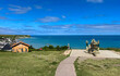 © framarzo - Arromanches in Normandy, France: World War II D-Day overlook with a German 88mm Flak gun, Mulberry B artificial harbor mural and historic concrete caissons ruins in the Atlantic Ocean.