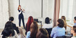 © master1305 - Female speaker presenting idea to audience in bright corporate seminar. Concept of business training, professional workshop, leadership coaching, public speaking, and education.