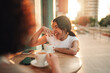 © Zamrznuti tonovi - Happy young woman laughing, enjoying coffee with friend at street cafe in warm sunset light