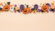 © MarufIslam - Festive halloween background with pumpkins and sweets arranged in a top border on a light orange surface