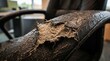 © Imam - Close-up of a severely damaged and worn-out office chair armrest, showing peeling faux leather and exposed padding.