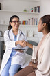 © fizkes - Cheerful confident mature doctor in lab coat shaking hands with young Black patient on consultation, expressing support. Young woman thanking practitioner for good healthcare news