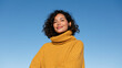 © ArtShop - Young woman smiling in a yellow sweater against the blue sky