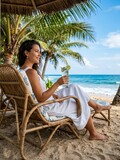 Woman relaxing on beach chair with cocktail by the ocean