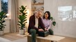 © Николай Срибяник - Senior man and adult daughter using projector to watch family photos in living room.