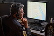 © pressmaster - Middle aged security guard monitoring digital map on desktop computer while speaking through headset in control room. Ideal for surveillance, dispatch, safety service marketing