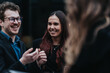 © qunica.com - Young professionals laughing and networking during an informal business conversation. Colleagues share a light moment while socializing outdoors.