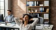 © Aura - Young woman wearing headset relaxing with eyes closed at her desk while a colleague works