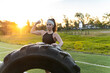 © Manu Prats/Stocksy - Strong athlete flexing her biceps beside a training tire