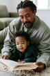 © Andrii Zastrozhnov - Father reading with toddler family bonding at home background for cozy parenting banner and shared storytime design